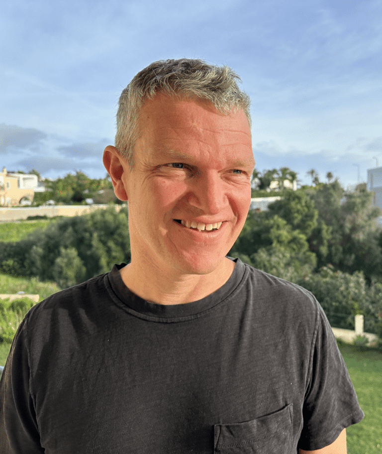 Person standing outdoors, blurred face.