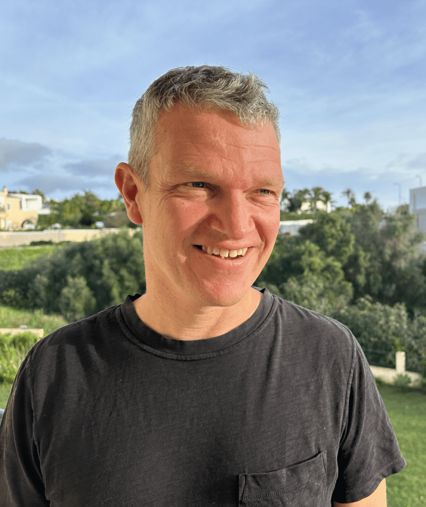 Person standing outdoors, blurred face.